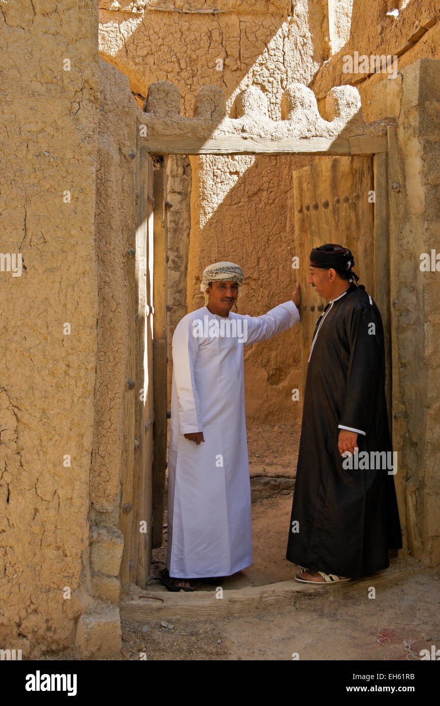 Gli uomini nella porta del vecchio edificio mudbrick, Al-Hamra, Oman Foto Stock