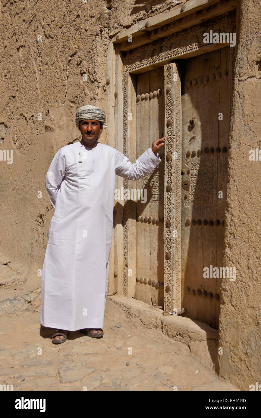 L uomo nella porta del vecchio edificio mudbrick, Al-Hamra, Oman Foto Stock