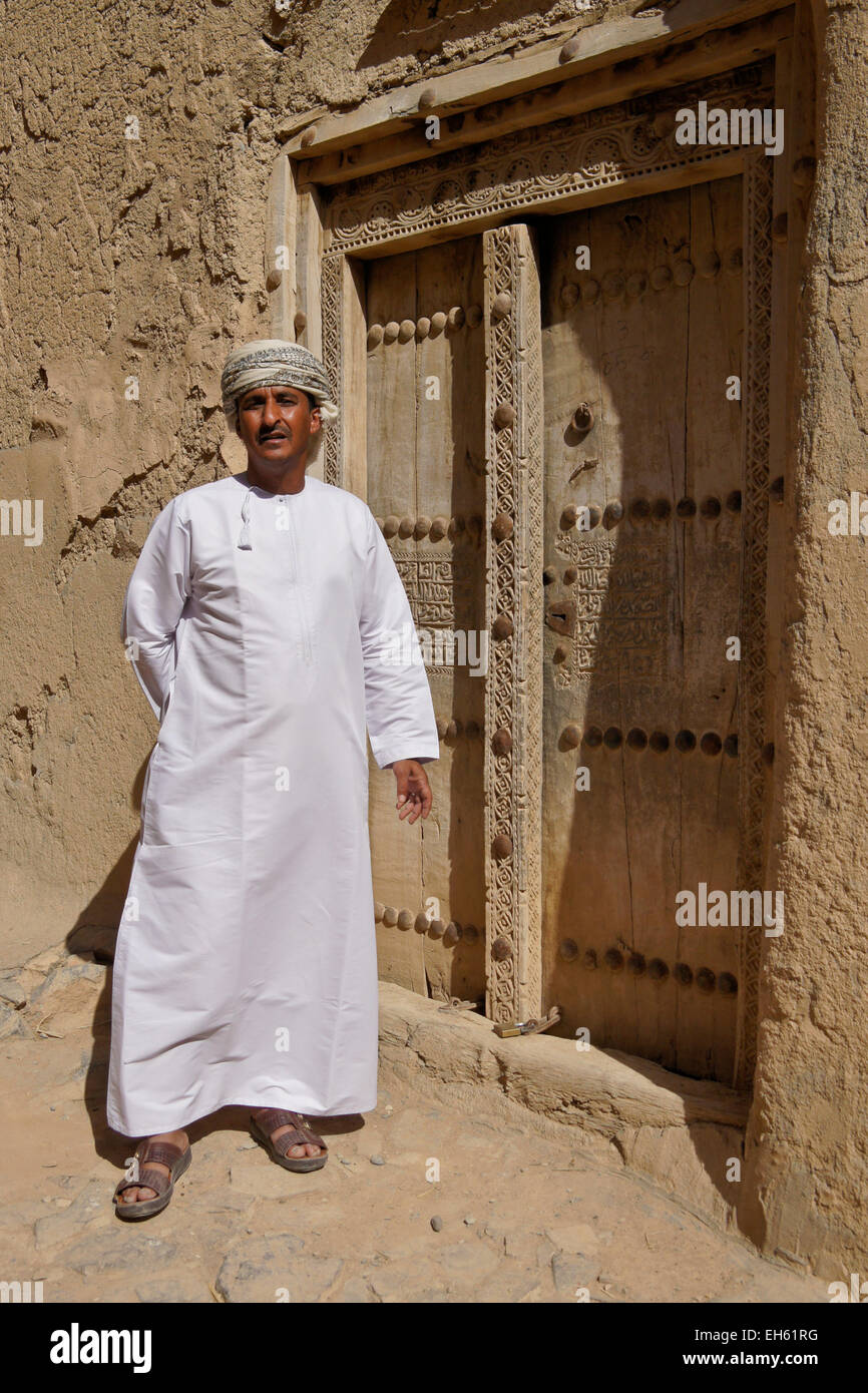 L uomo nella porta del vecchio edificio mudbrick, Al-Hamra, Oman Foto Stock