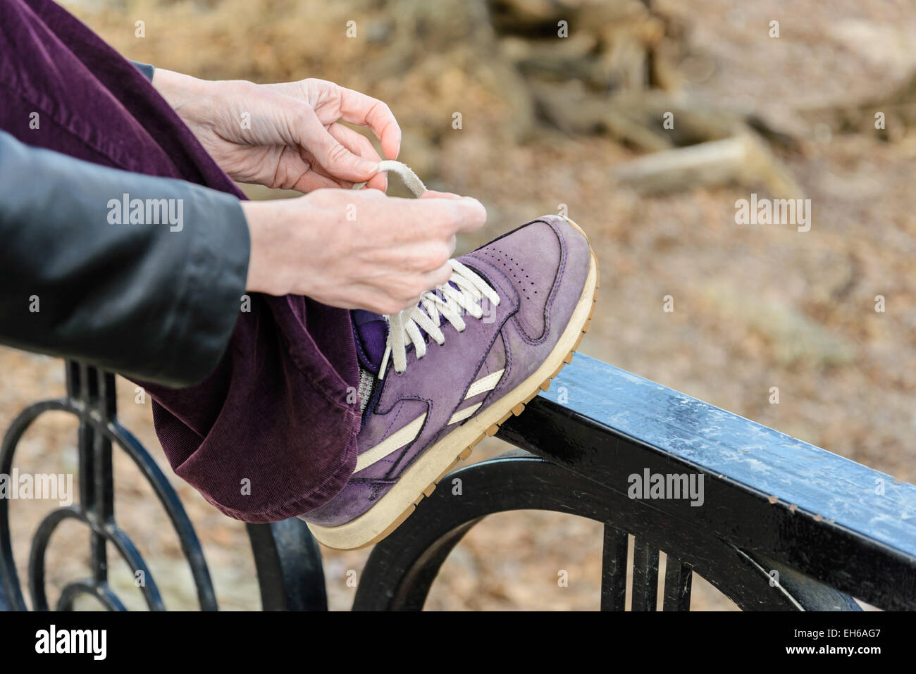 Una donna è la sua legatura viola con le scarpe con i lacci bianco, durante una calda giornata di escursioni in montagna Foto Stock