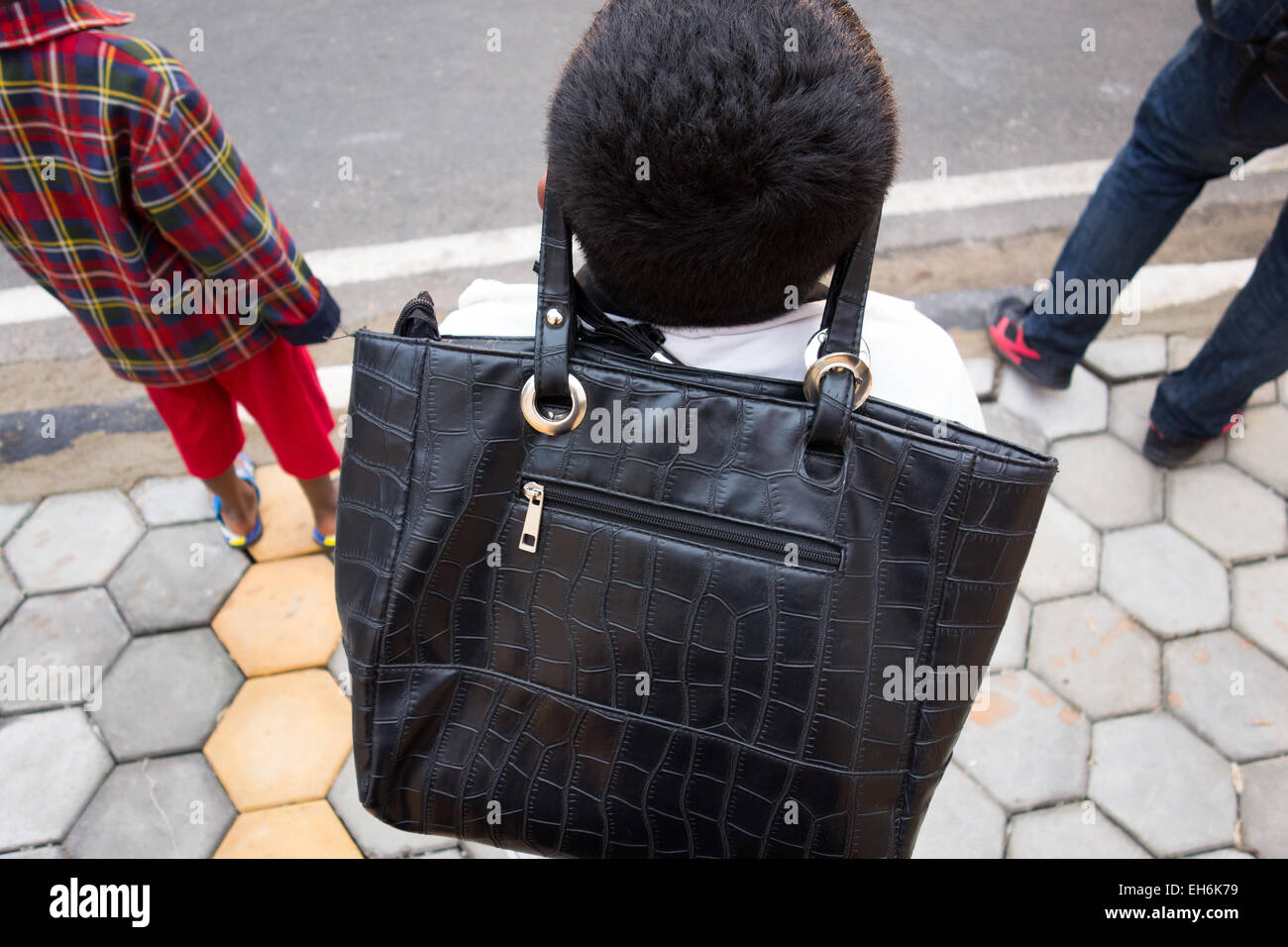 Ragazzo indiano indossa una donna di borsa sulla sua fronte Foto Stock