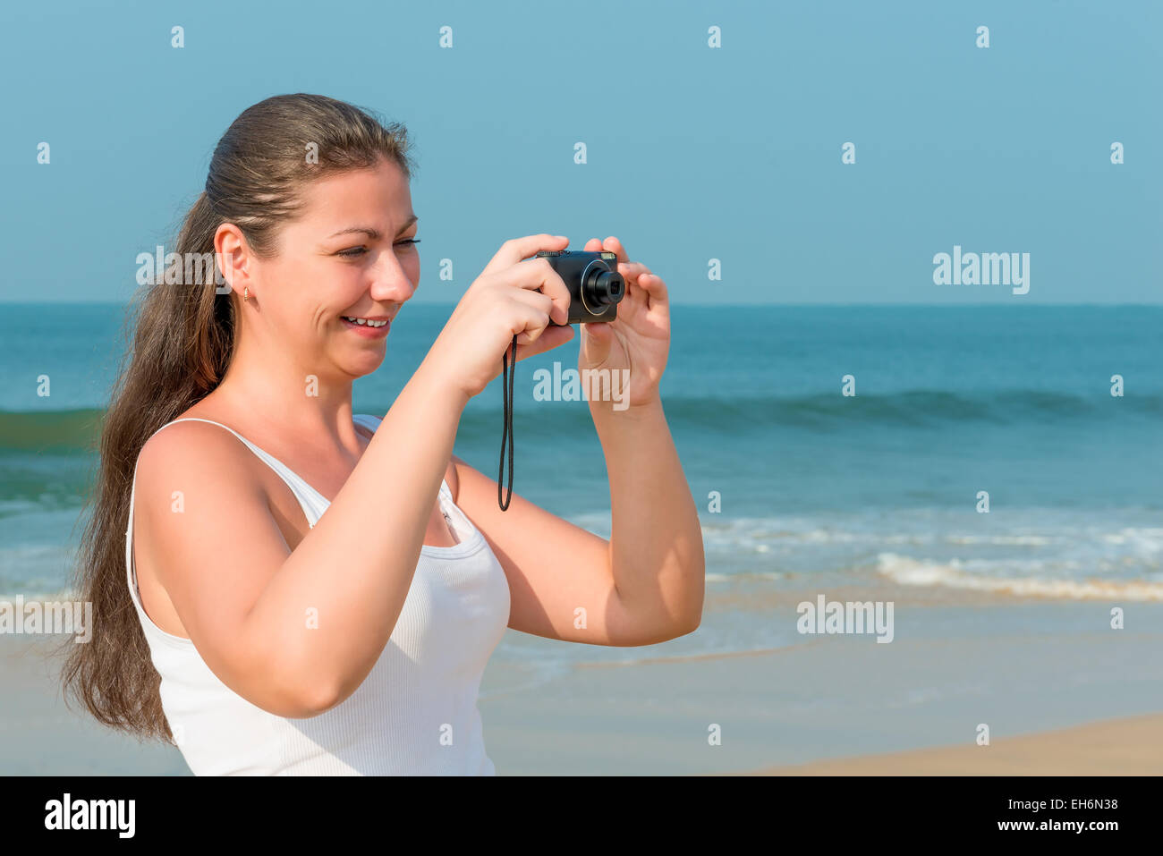 Felice bellissima ragazza con la fotocamera in mano da mare Foto Stock