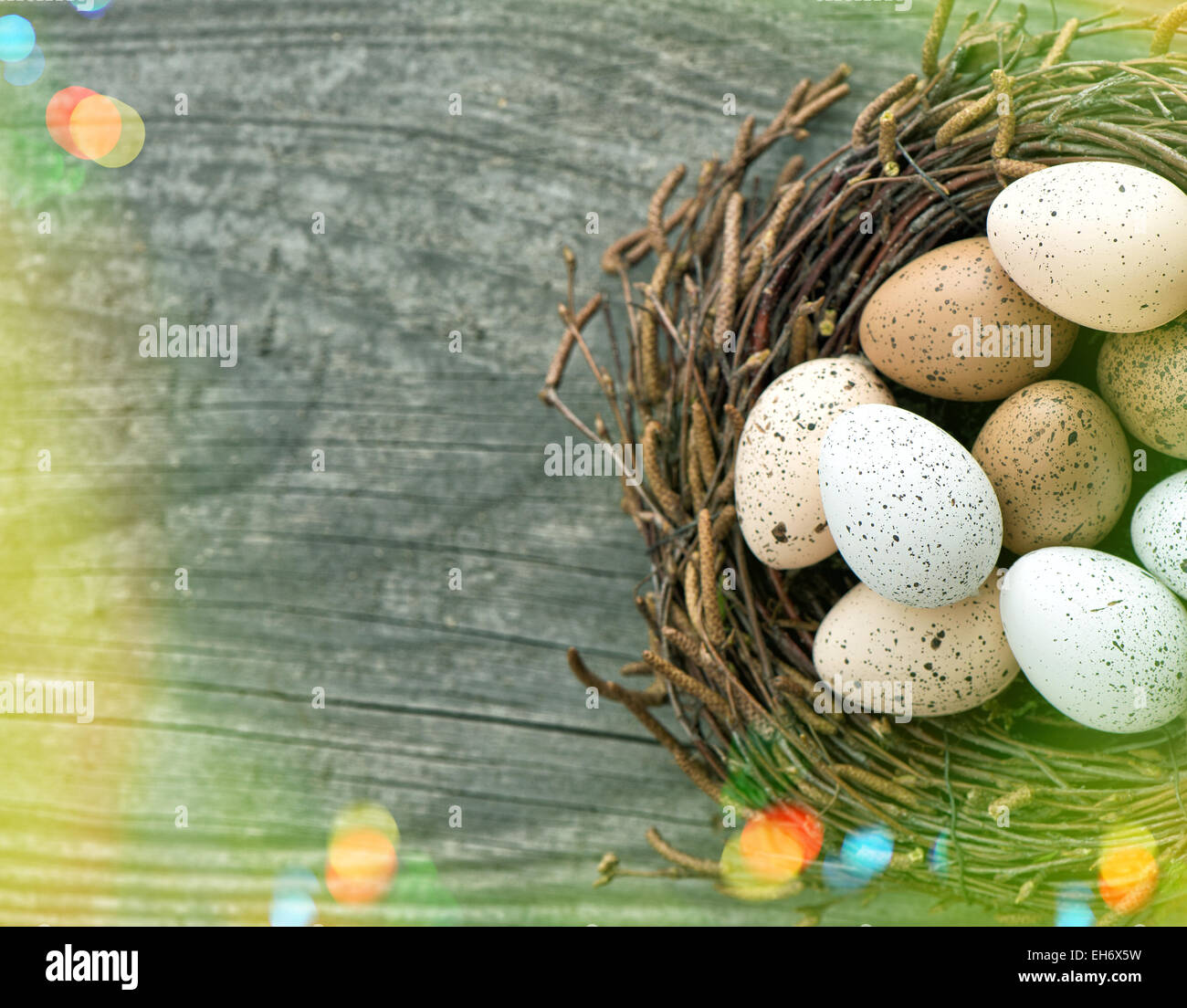 Uova di Pasqua nel nido su sfondo di legno. In stile retrò tonica immagine con perdite della luce Foto Stock