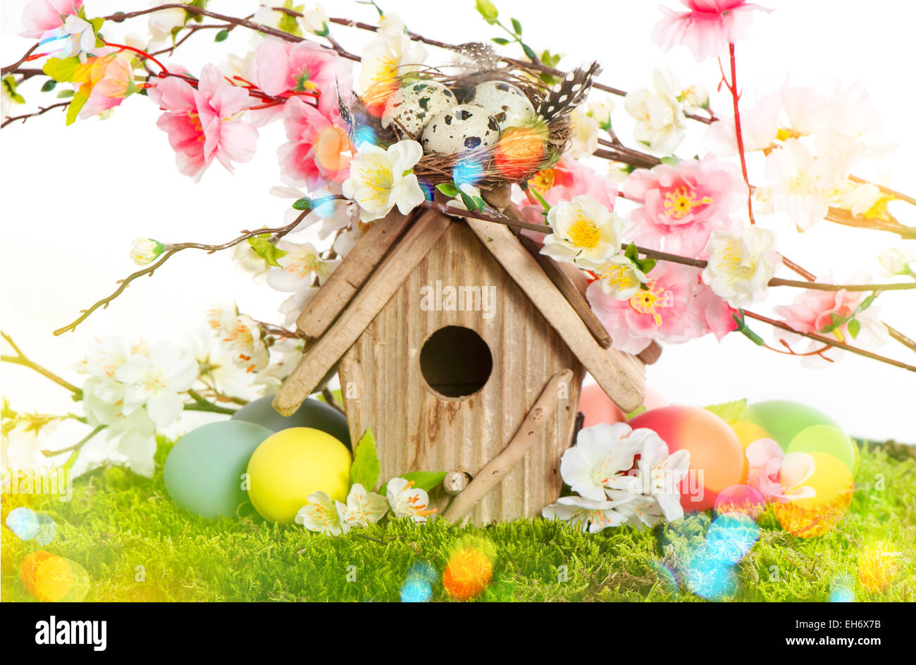 Decorazione di pasqua con birdhouse e uova su erba verde. La molla di Apple e di fiori di ciliegio. In stile retrò tonica foto con luce Foto Stock