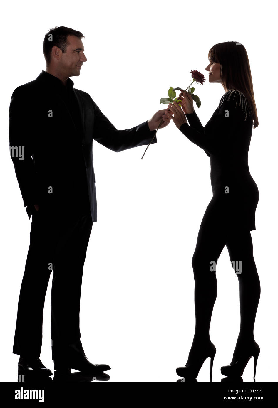 Uno gli amanti caucasico giovane uomo offrendo fiori di rose e la donna maleodoranti in studio silhouette isolati su sfondo bianco Foto Stock