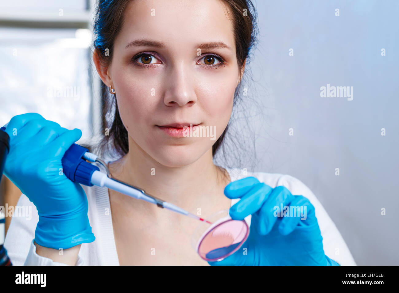 Donna che mantiene una pipetta e capsula di petri Foto Stock