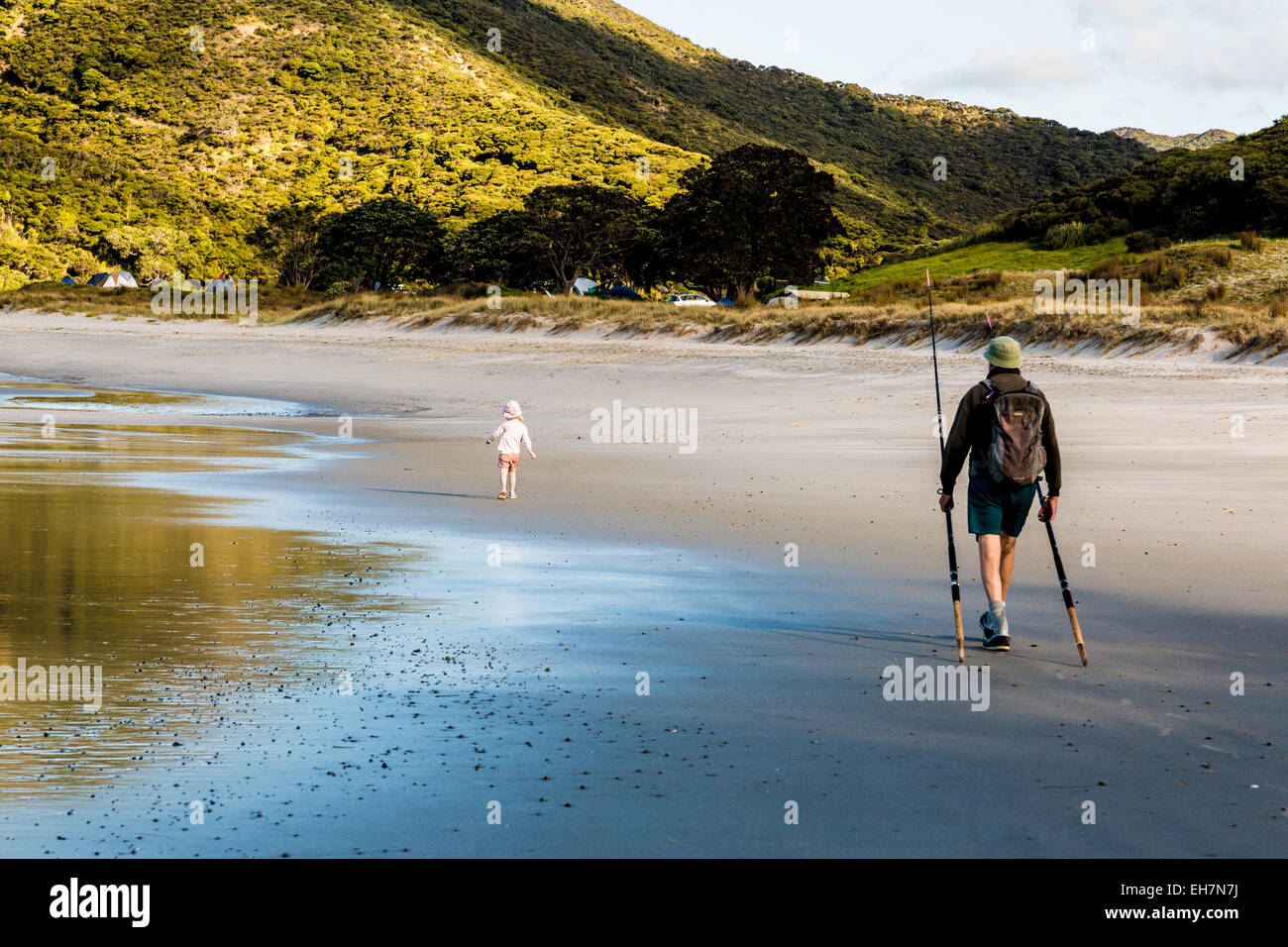 Ragazza giovane e suo nonno camminando lungo una spiaggia dopo un viaggio di pesca Foto Stock