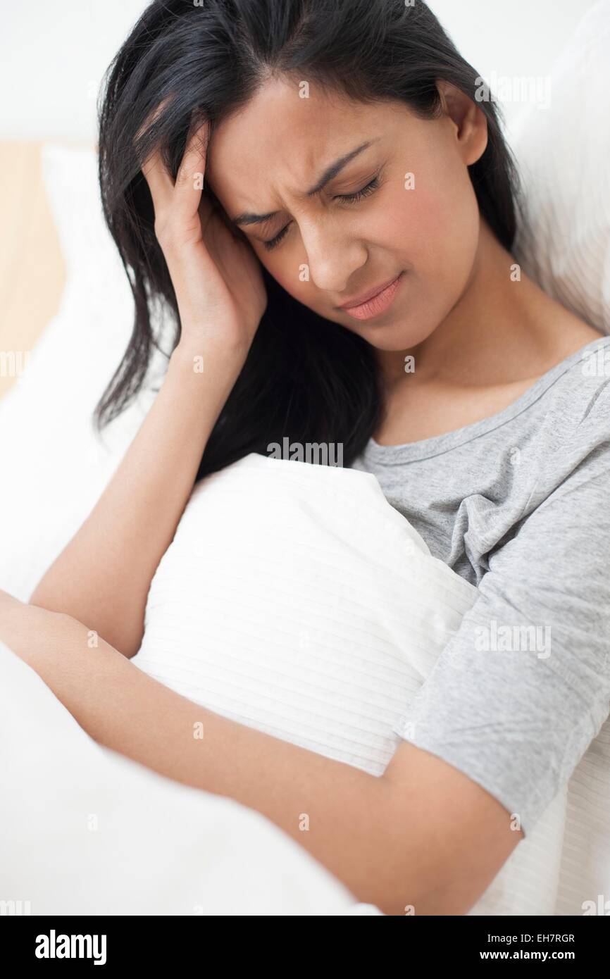 Donna nel letto di toccare la sua testa Foto Stock