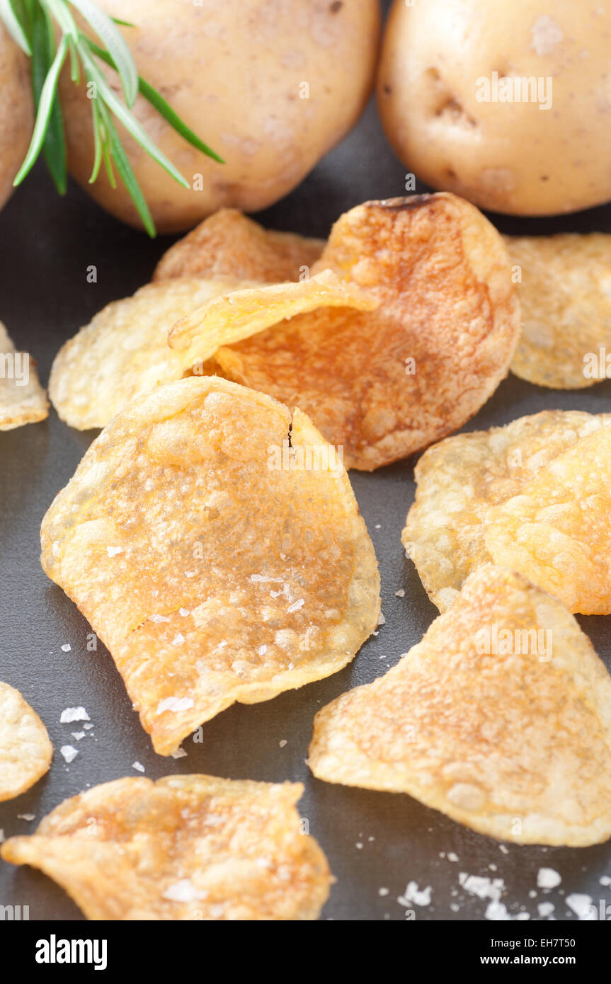 Patate fritte con sale marino. Materie di patate con rosmarino in background. Foto Stock