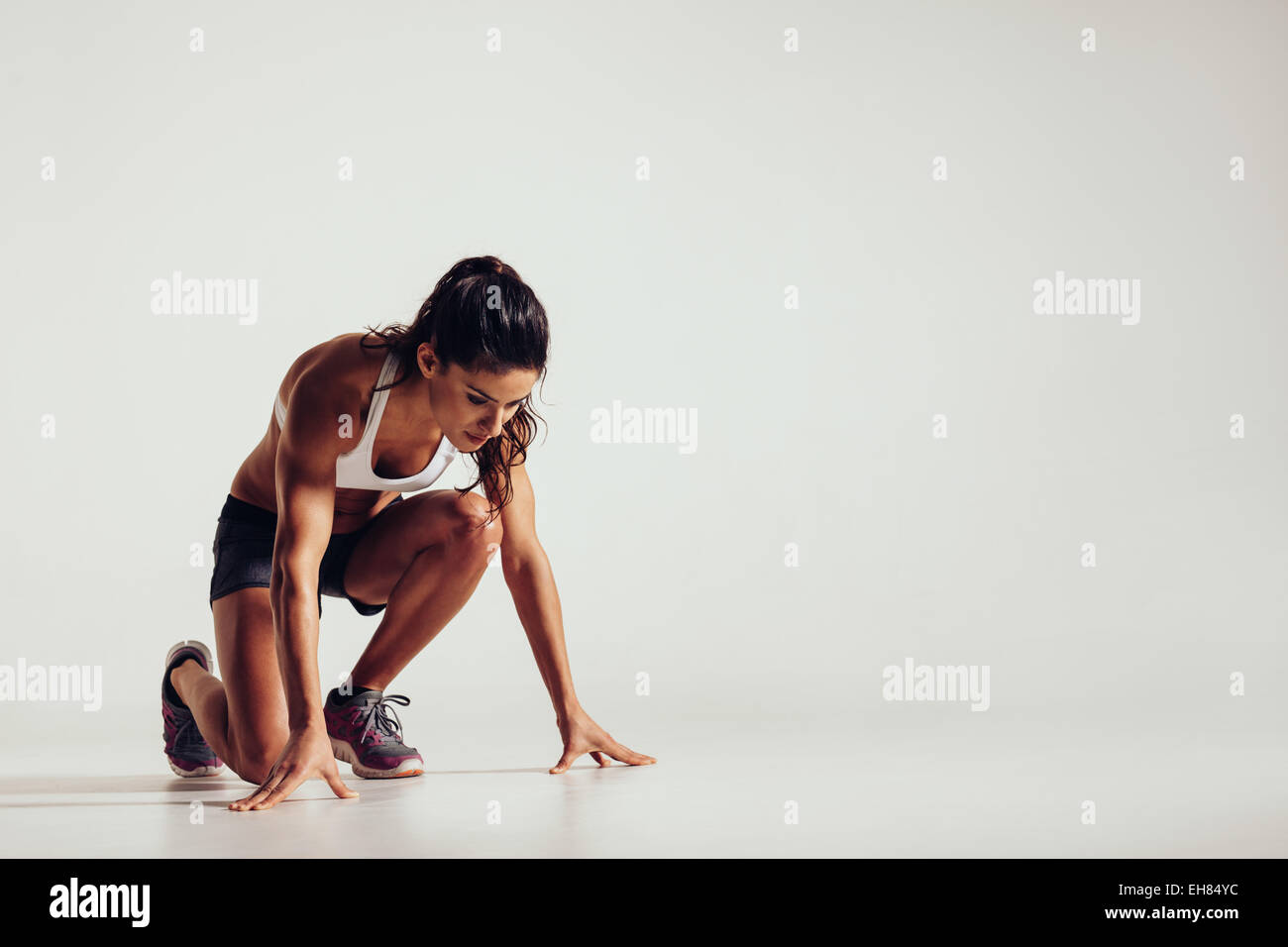 Sano giovane donna preparando per un'esecuzione. Montare atleta femminile pronto per una molla su uno sfondo grigio con copia spazio. Foto Stock