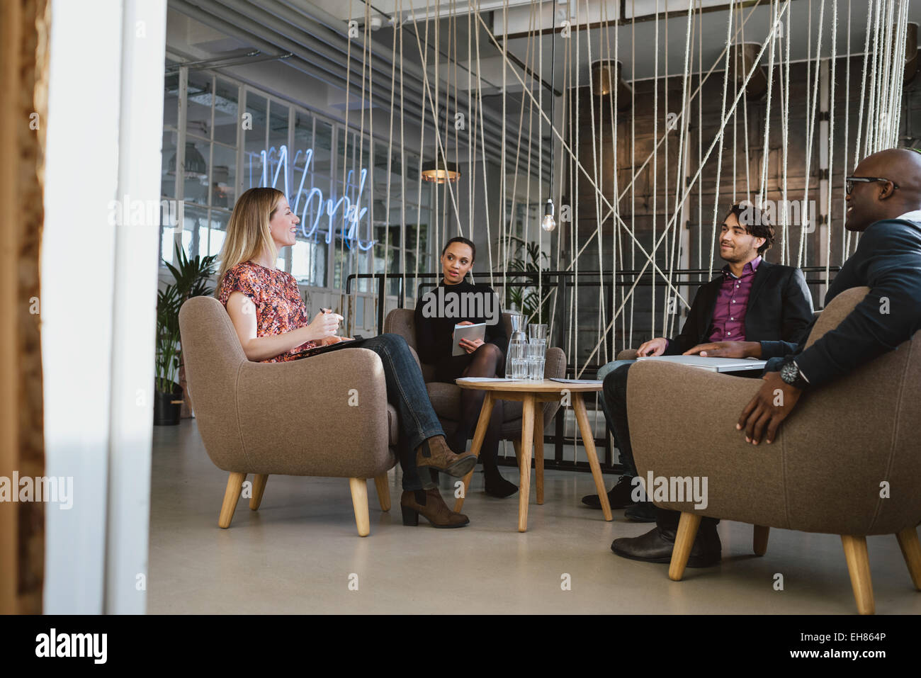 Felice giovani seduti insieme in office discutere di affari. Ufficio i lavoratori aventi un incontro nella lobby. Business diversi pe Foto Stock