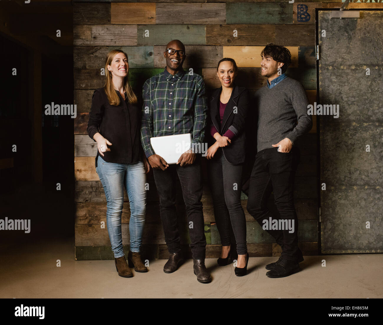 Ritratto di giovani professionisti di ridere mentre in piedi insieme in ufficio. Multi etnico team business cercando felice insieme. Foto Stock