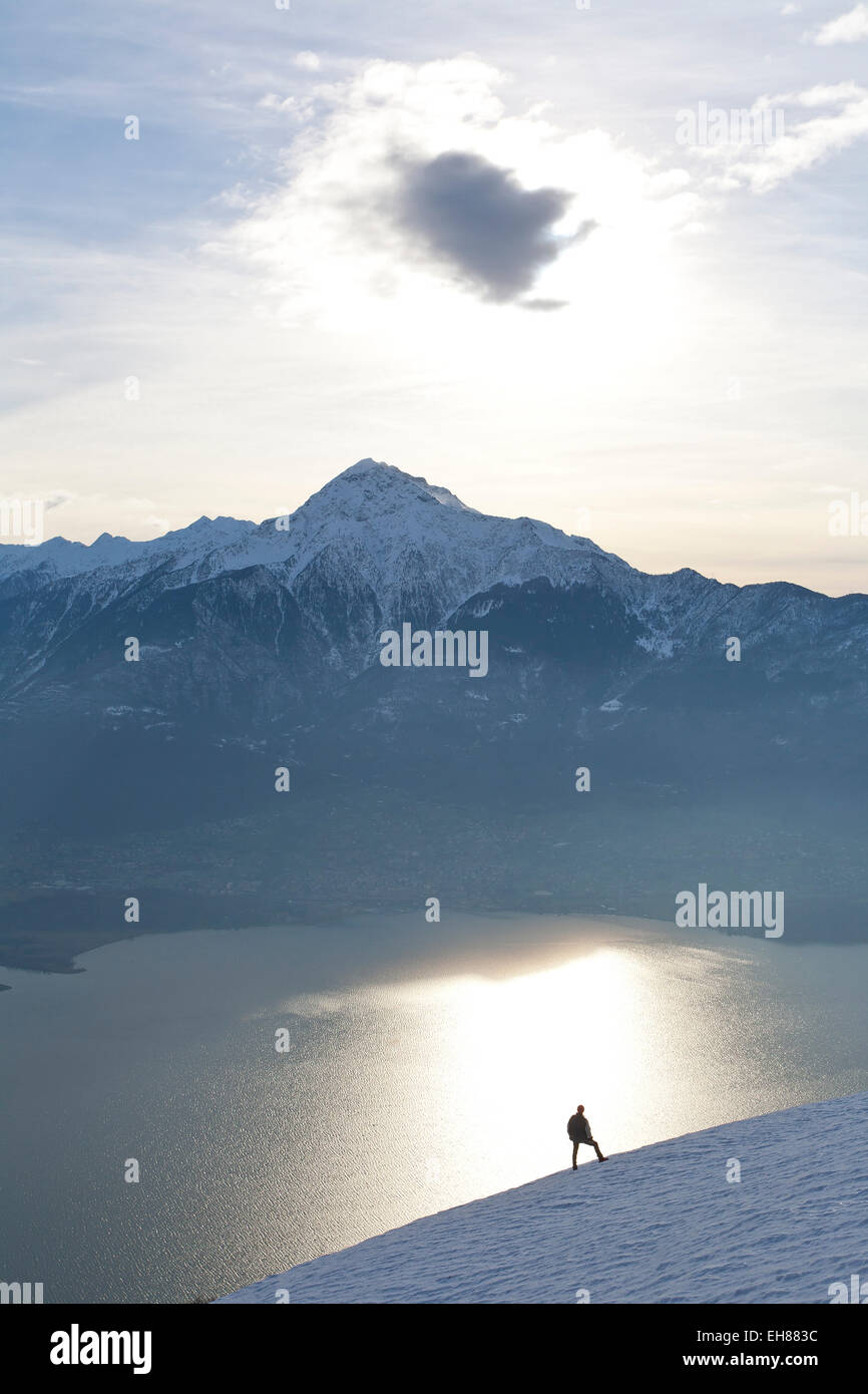 Silhoutte di un escursionista rivolta verso il Monte Legnone e il Lago di Como al tramonto, Lombardia, Italia, Europa Foto Stock