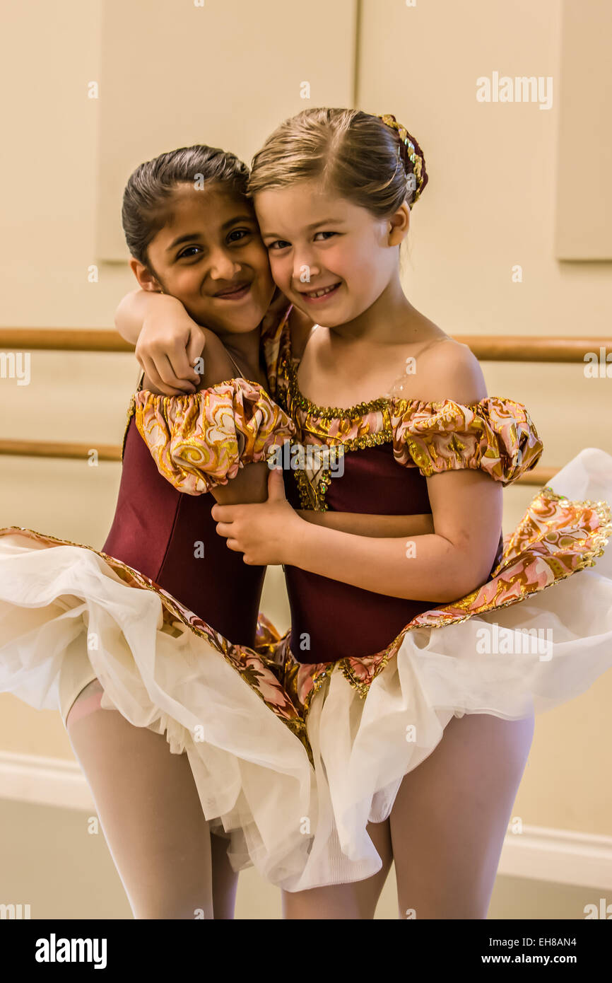 Sette anni di ragazze abbracciava, mostrando la loro amicizia, in un balletto danza prove abito in un monolocale Foto Stock