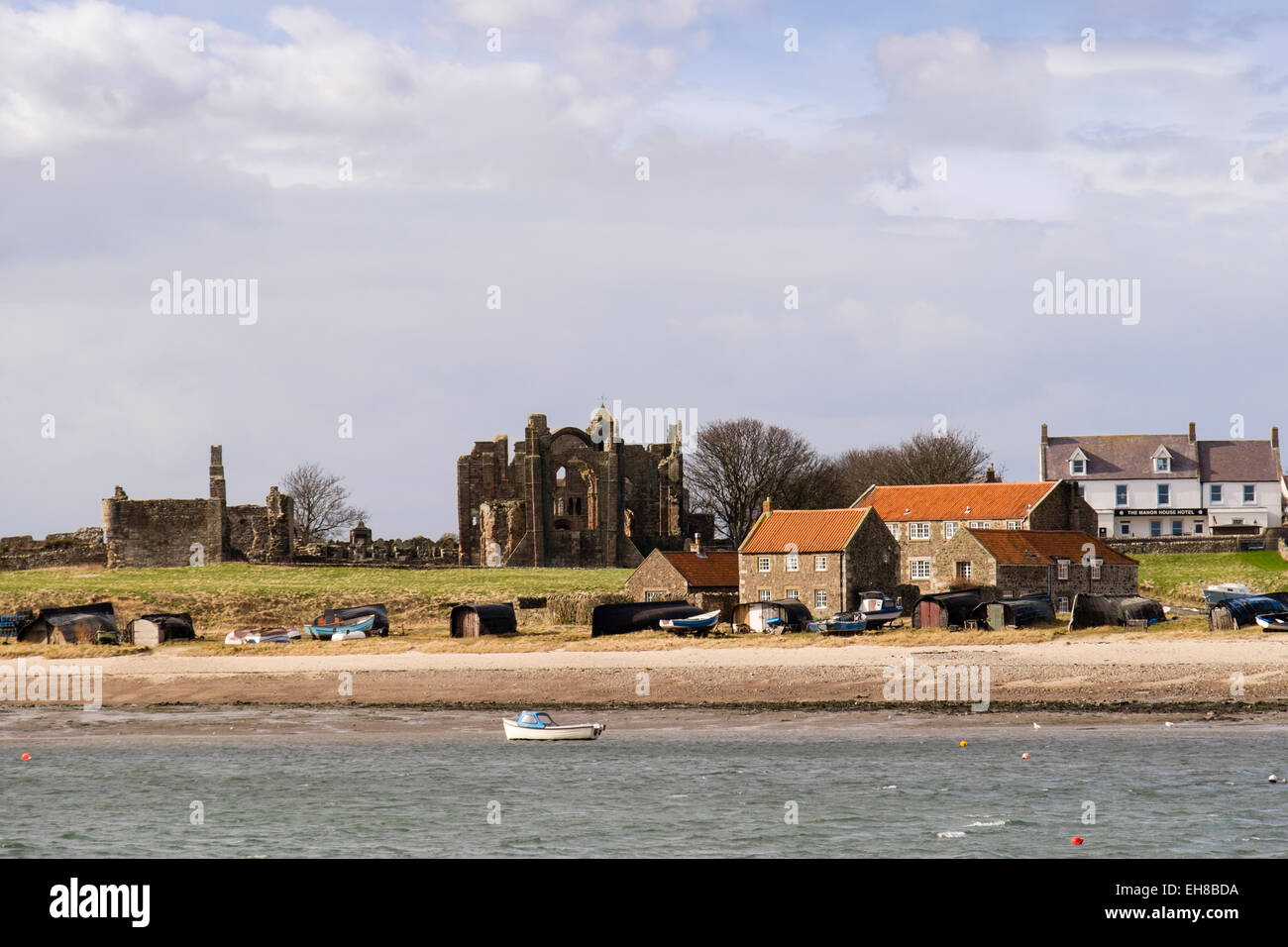 Lindisfarne Priory e Manor House Hotel visto da tutta l'acqua. A Isola Santa, Northumberland, Inghilterra, Regno Unito, Gran Bretagna Foto Stock