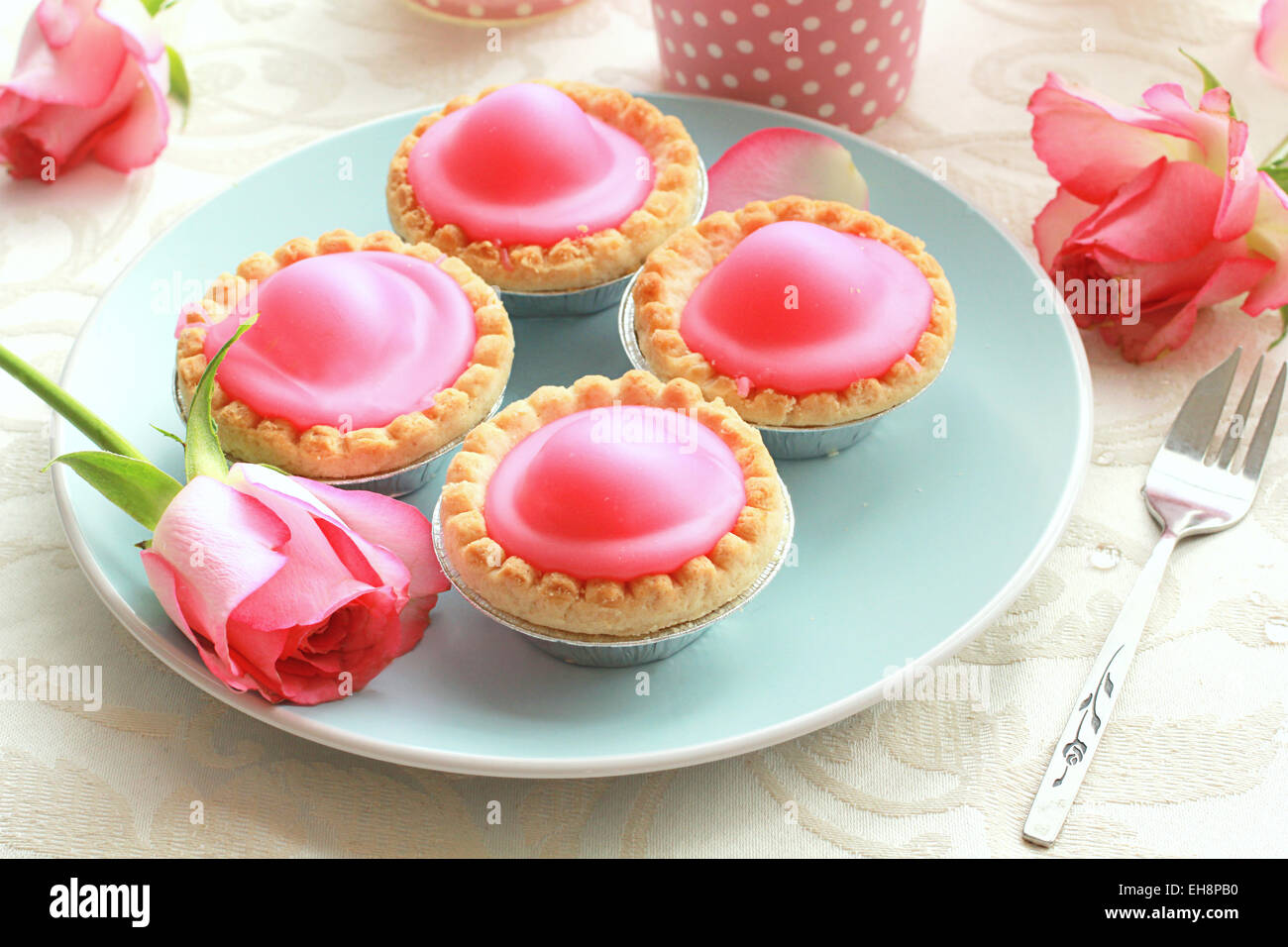 Torte di rosa sulla piastra blu con le rose rosa Foto Stock