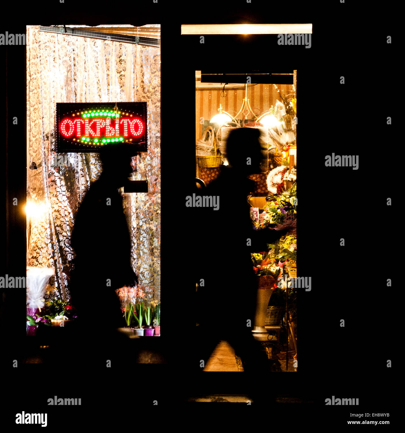 Due uomini sconosciuto vai al buio dal negozio di fiori con la piastra splendente apertamente Foto Stock
