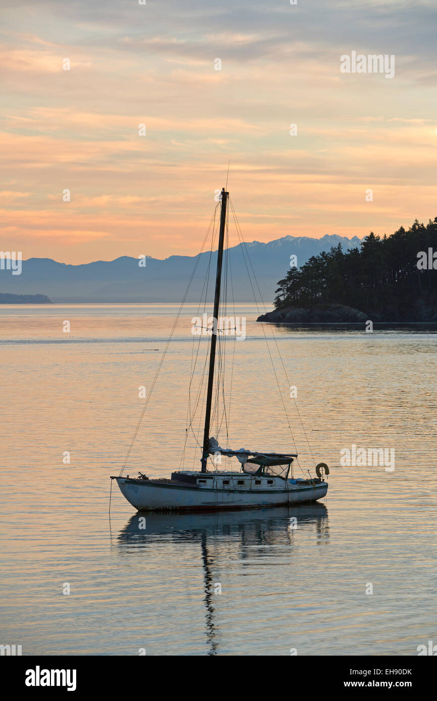 Una imbarcazione a vela è al sicuro nel porto di Bowman Bay sulla Whidbey Island al tramonto. Foto Stock