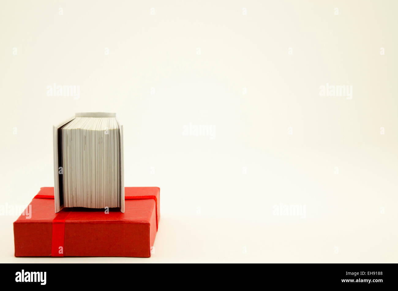Casella rossa coperchio e un piccolo libro su bianco Foto Stock