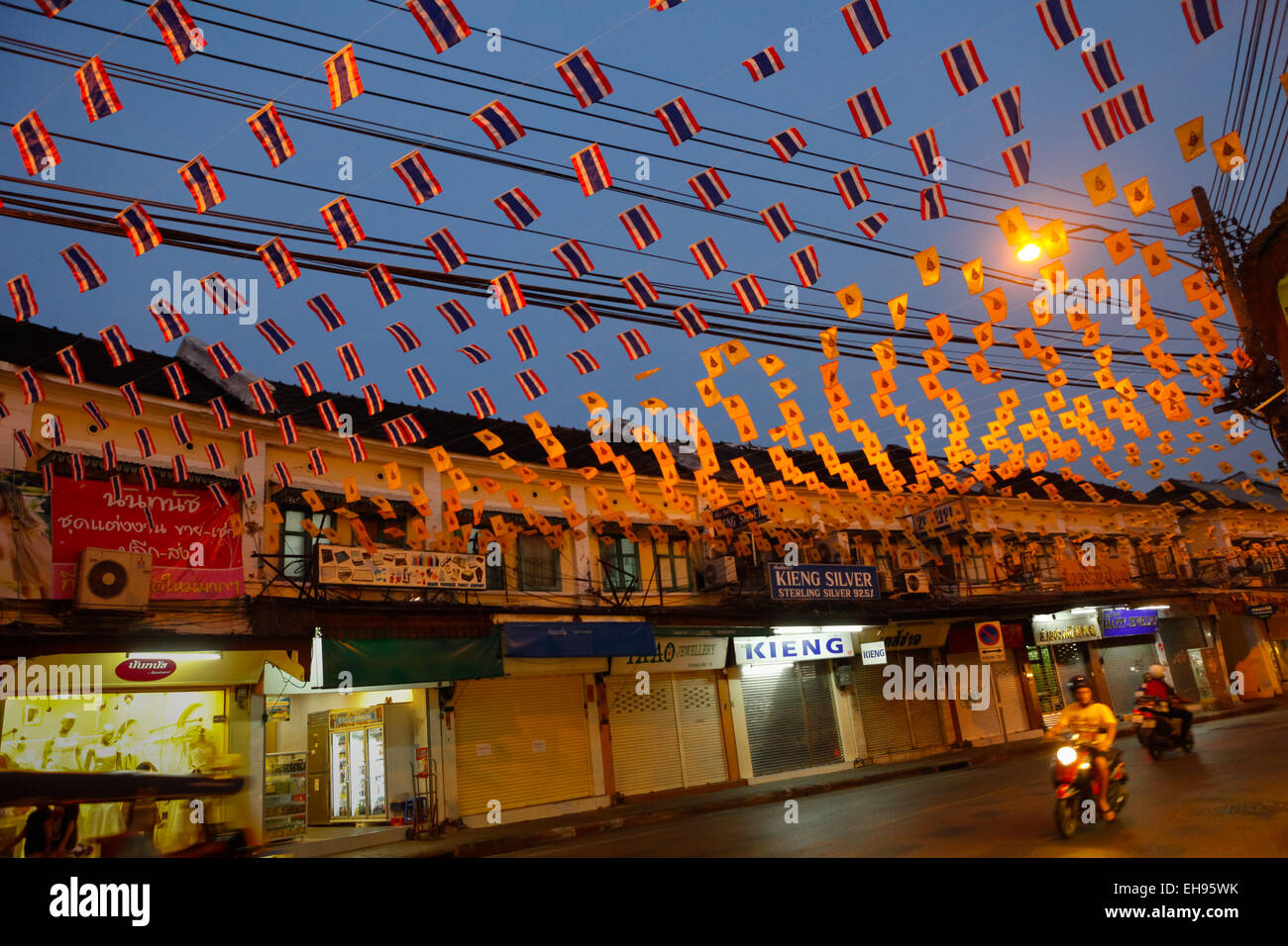 Automobilisti che cavalcano di notte sotto le bandiere decorative su via Tanao nella zona di Khaosan Road, Bangkok, Thailandia. Foto Stock