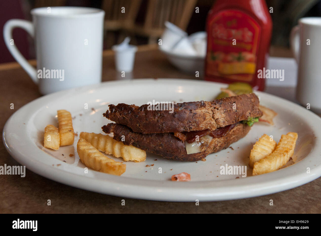 La crosta del sandwich incompiuto sulla piastra con patate fritte Foto Stock