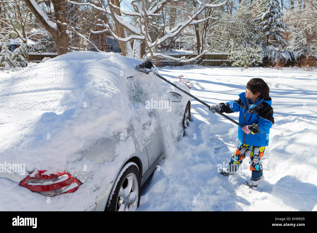 Bambino neve di pulizia al di fuori della macchina utilizzando la ginestra - Virginia STATI UNITI D'AMERICA Foto Stock