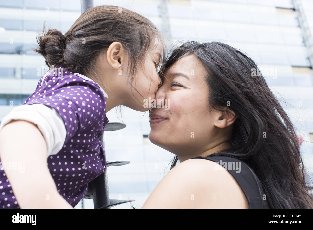 Ragazza baciare la madre del naso all'aperto Foto Stock
