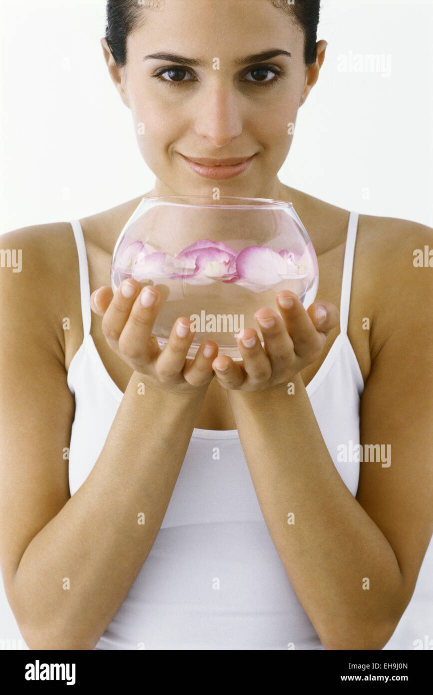 Donna che mantiene una ciotola di petali galleggianti in acqua Foto Stock