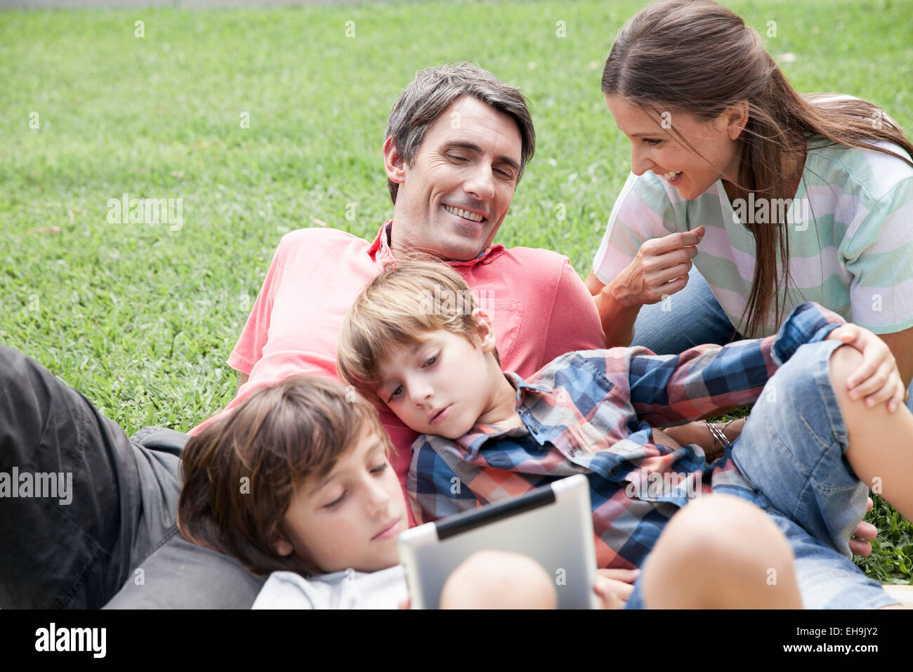 Famiglia con due bambini di trascorrere il pomeriggio presso il park, giovani ragazzi con tavoletta digitale Foto Stock