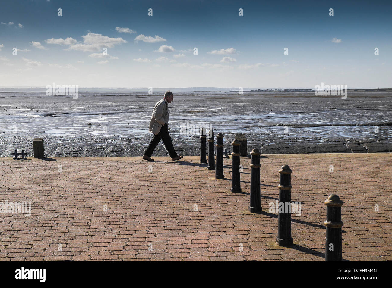 Un uomo che cammina su una banchina a Leigh on Sea in Essex. Foto Stock