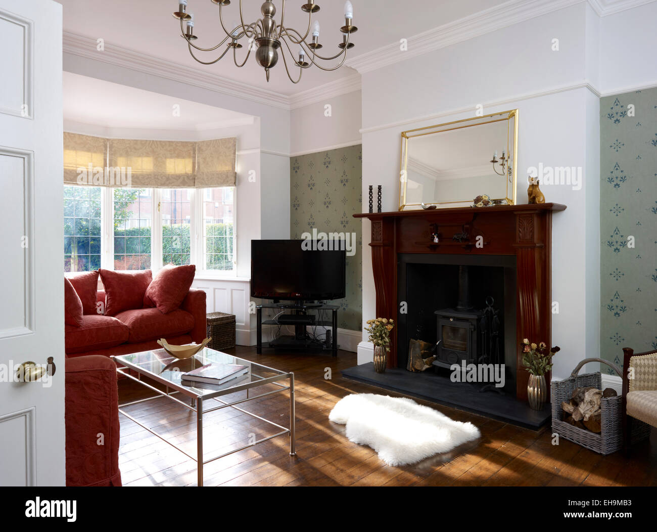 La stanza di seduta con finestra di baia, lampadario e stufa a legna nel camino, casa residenziale, Kingsmead, REGNO UNITO Foto Stock