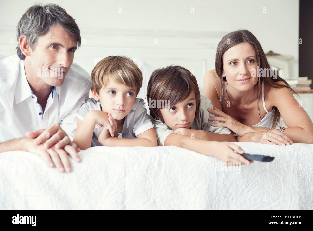 Famiglia di guardare la TV sul letto, ritratto Foto Stock