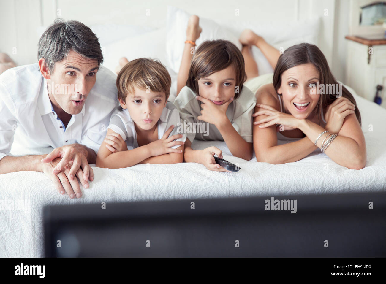 Famiglia di guardare la TV sul letto, ritratto Foto Stock