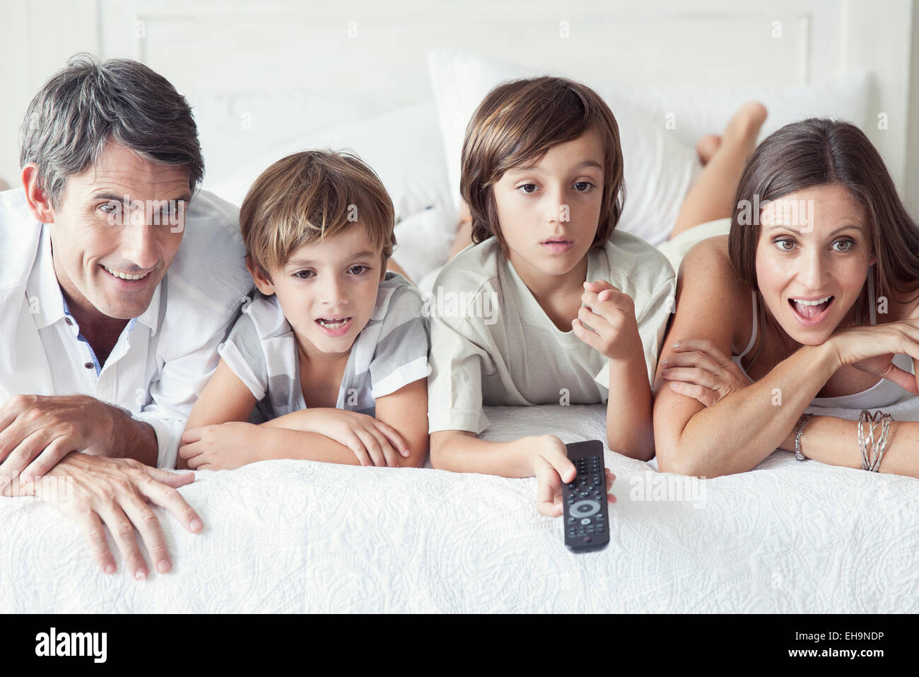 Famiglia di guardare la TV sul letto, ritratto Foto Stock