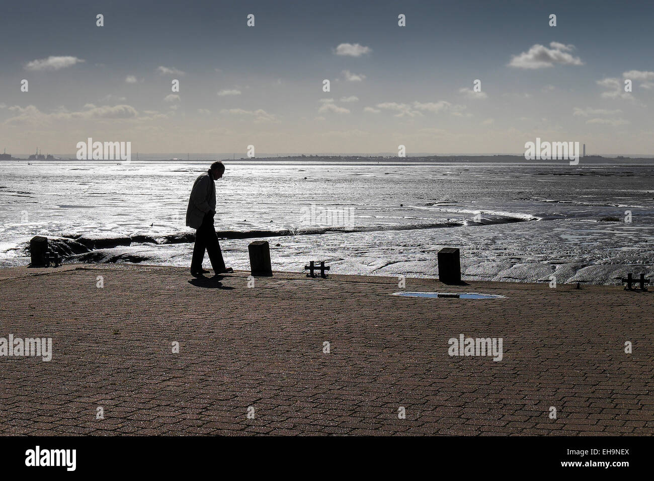 La silhouette di un uomo che cammina su una banchina a Leigh on Sea in Essex. Foto Stock