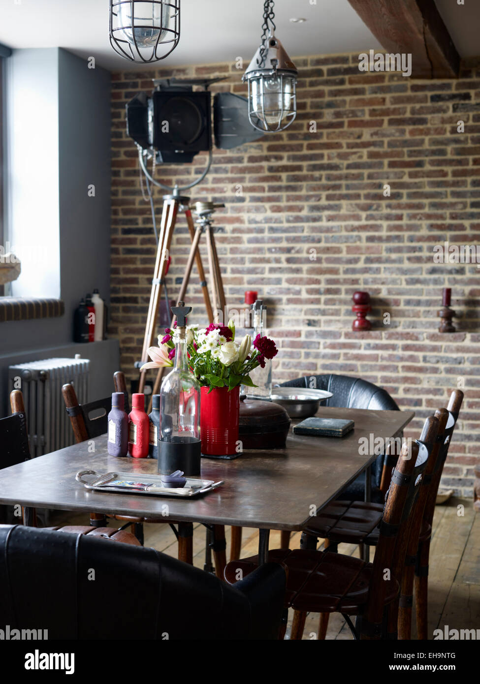 Tavolo in legno con fiori e pendente illuminazione industriale nella zona pranzo di Corbetts Wharf apartments, REGNO UNITO Foto Stock