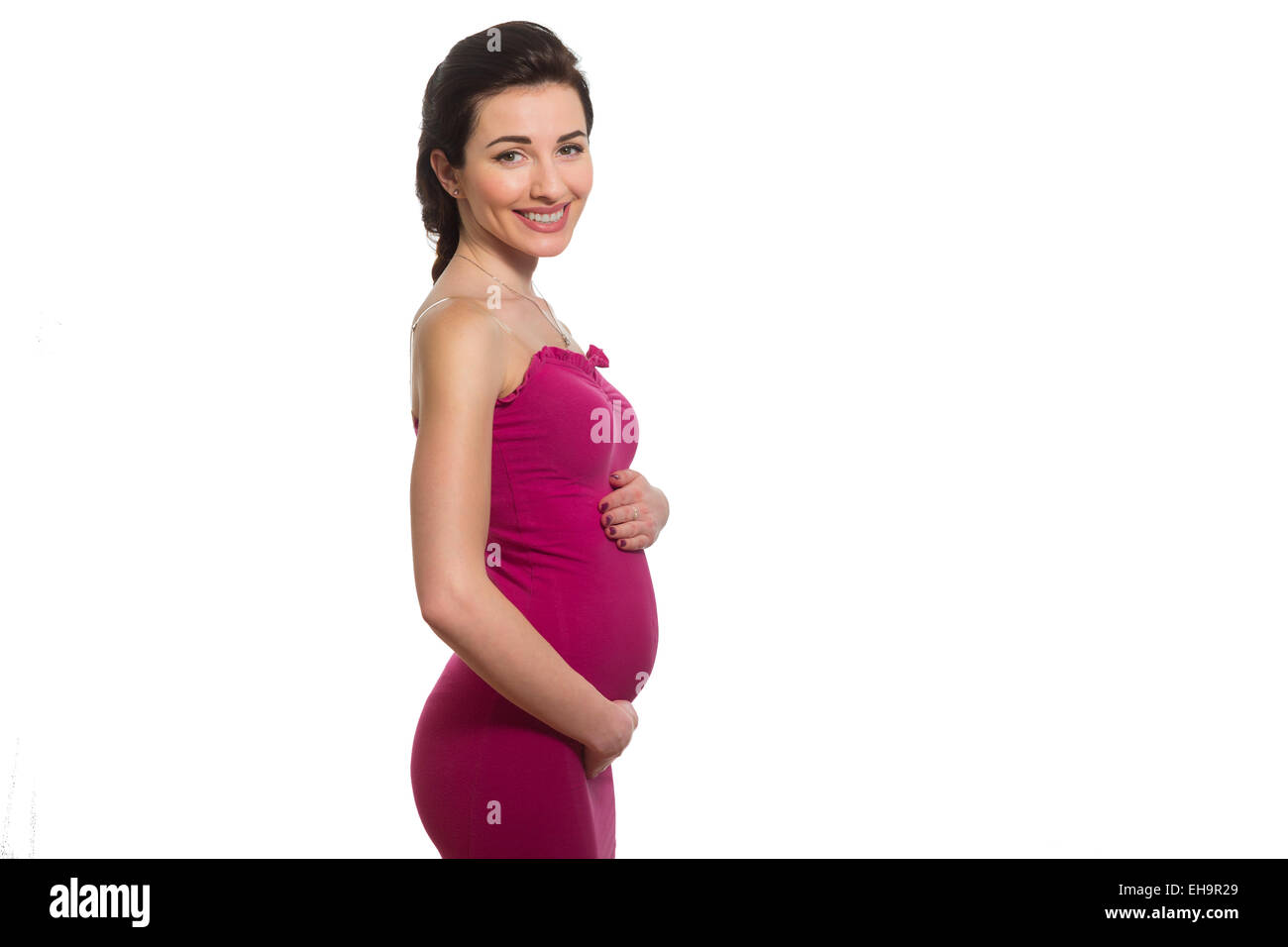 Giovani caucasici incinta sorridente signora in Rosa vestire toccando ventre in profilo isolato su sfondo bianco Foto Stock