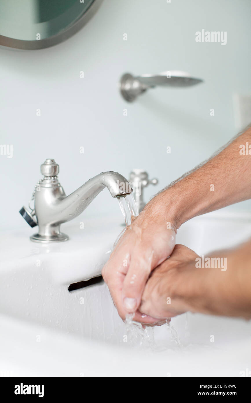L'uomo lavarsi le mani nel lavandino del bagno Foto Stock