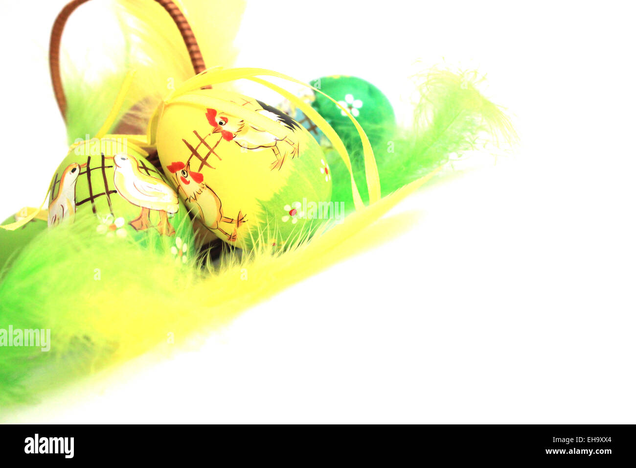 Uova di Pasqua nel cestello con piume colorate isolati su sfondo bianco Foto Stock