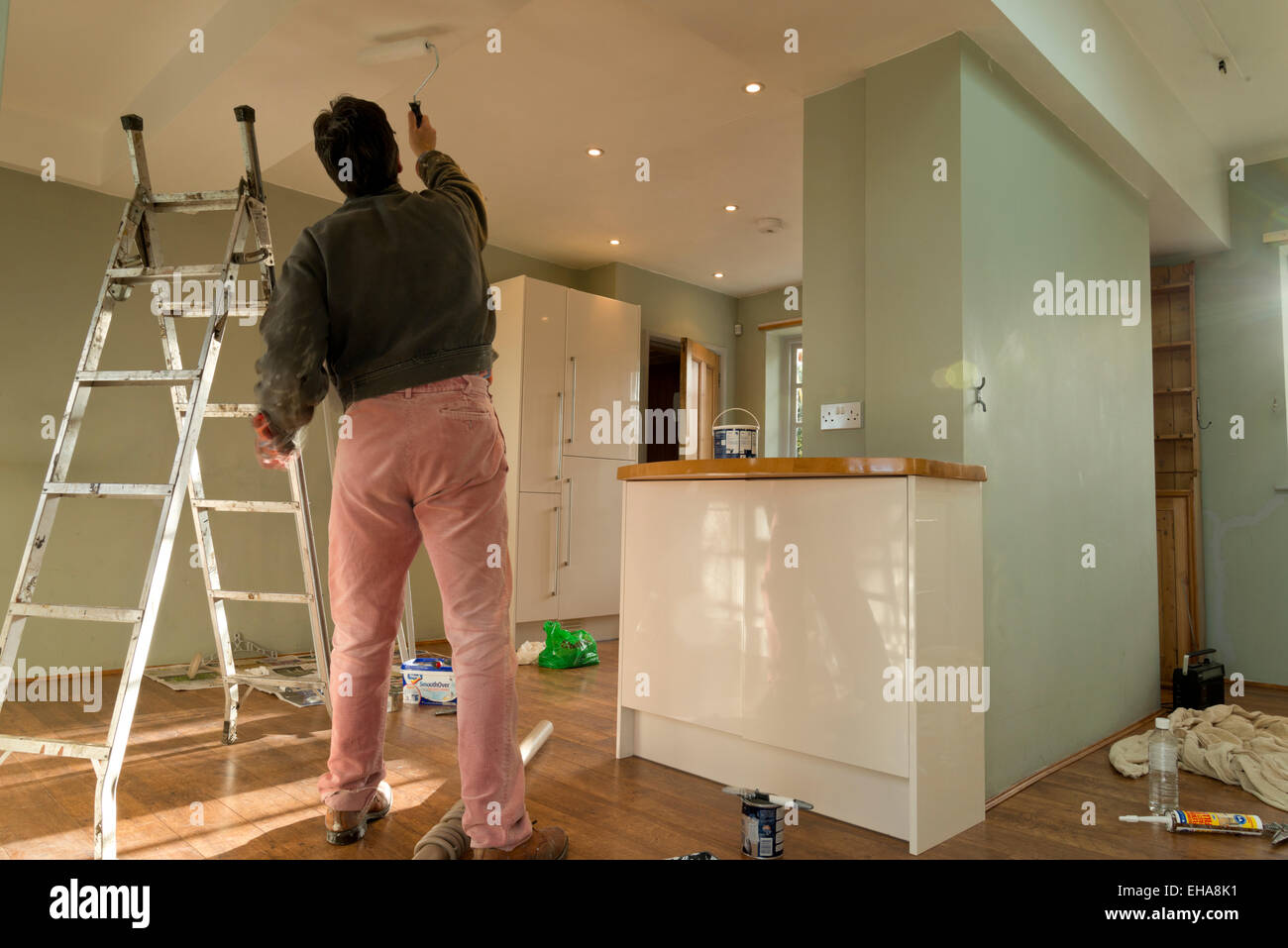 Uomo che utilizza un rullo di vernice sul soffitto. Decorare la cucina di una casa. Foto Stock