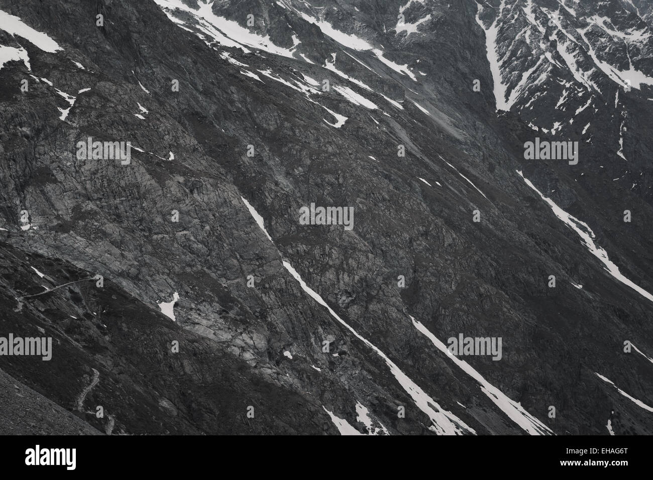 Grigio, sterile, innevato paesaggio di montagna con percorso di avvolgimento nel Parco Nazionale degli Ecrins, sulle alpi francesi. Foto Stock