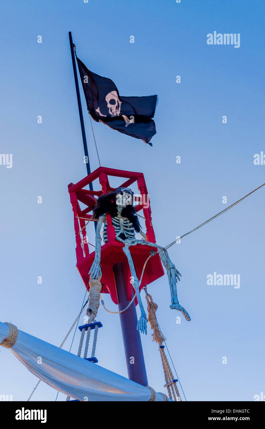 Scheletro a Davy Jones's locker. sulla cima di una nave pirata montante e Jo;lly Rodger bandiera,. Foto Stock