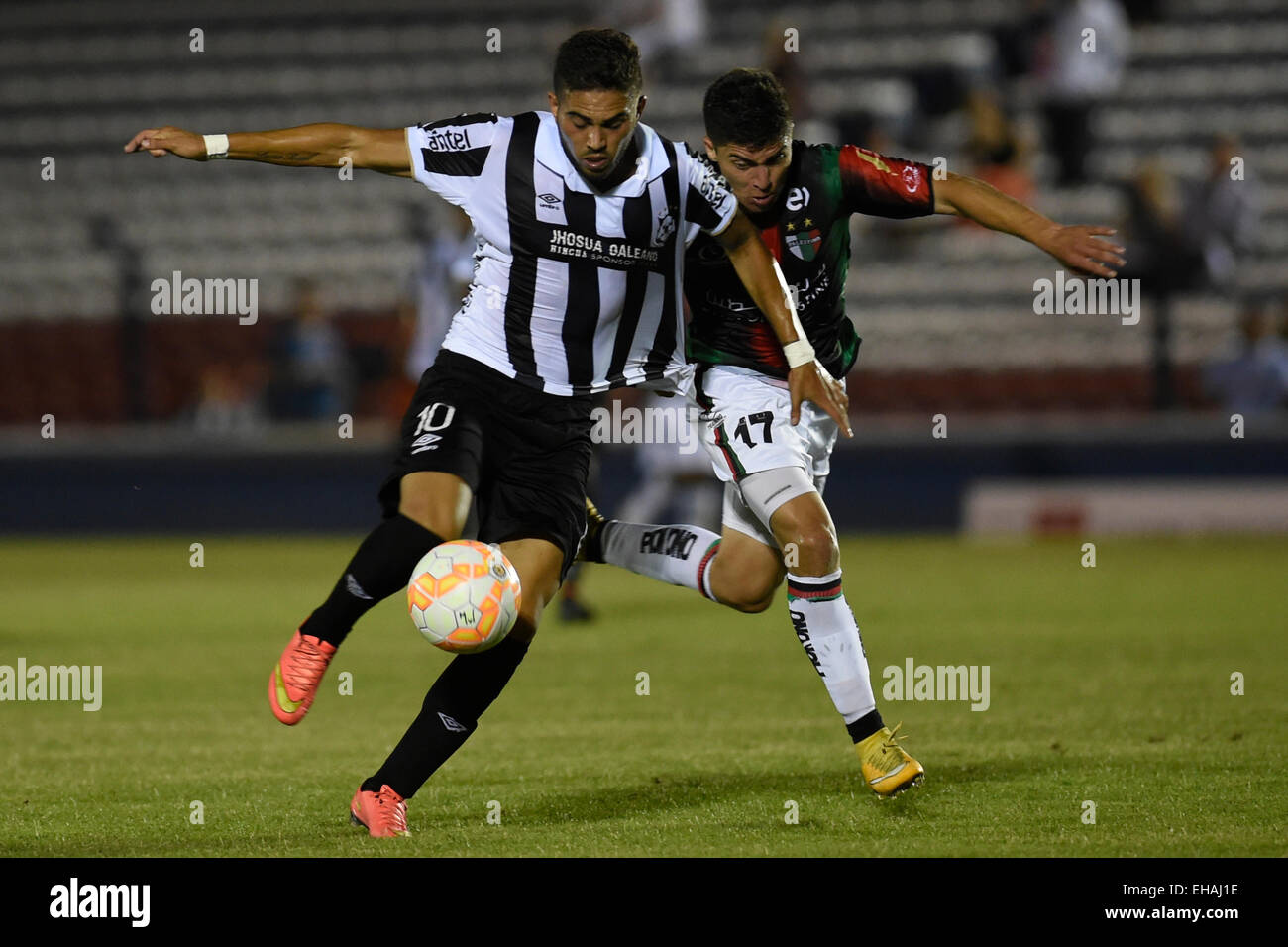 Montevideo, Uruguay. Decimo Mar, 2015. Il Wanderers Nicolas Albarracin (L) dell'Uruguay il sistema VIES per la palla con Palestino's Esteban Carvajal del Cile durante il match di Copa Libertadores nel Gran Parque Central Stadium di Montevideo, capitale dell'Uruguay, 10 marzo 2015. © Nicolas Celaya/Xinhua/Alamy Live News Foto Stock