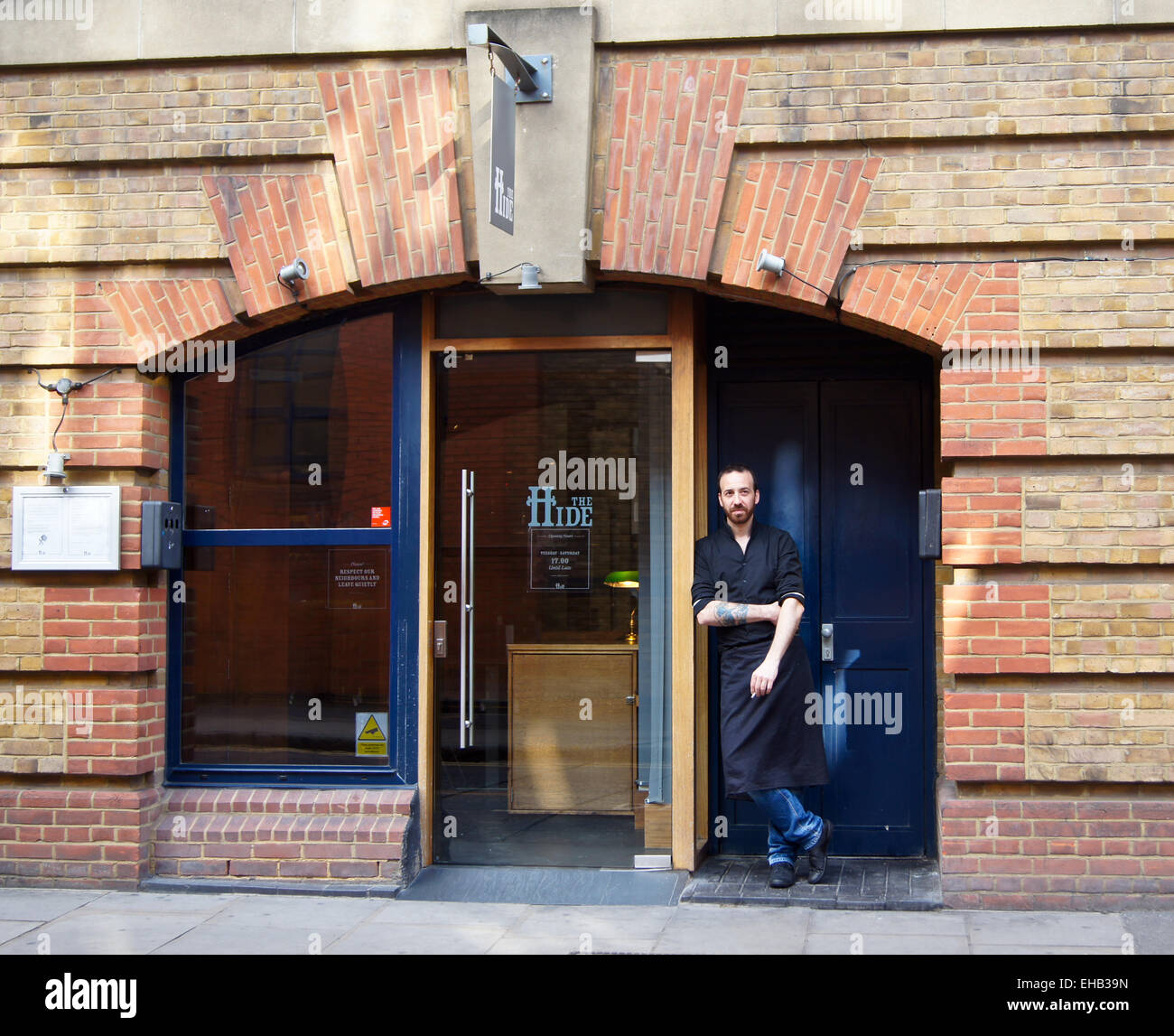 Un tatuato cameriere di fumare al di fuori del bar Nascondi, Bermondsey Street, Londra, Inghilterra Foto Stock