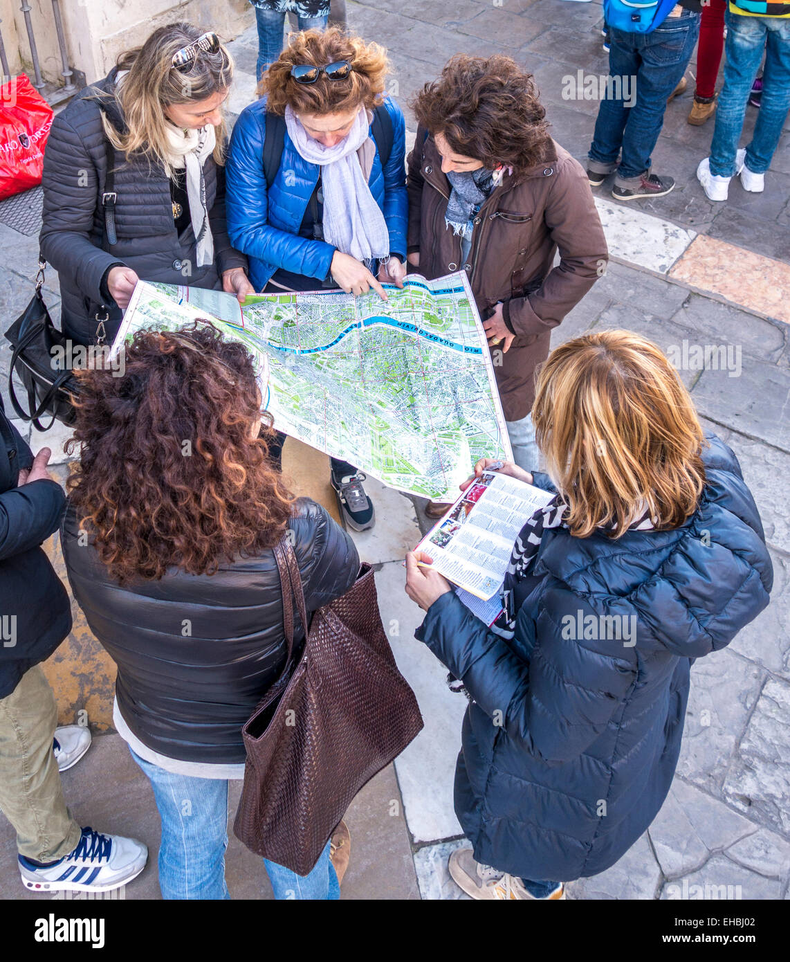 Il gruppo di cinque ragazze e giovani donne, i turisti alla ricerca di una mappa turistica di Siviglia Spagna puntamento e discutendo le direzioni Foto Stock