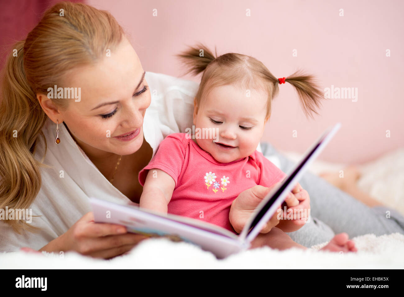 Madre felice di leggere un libro per bambina Foto Stock