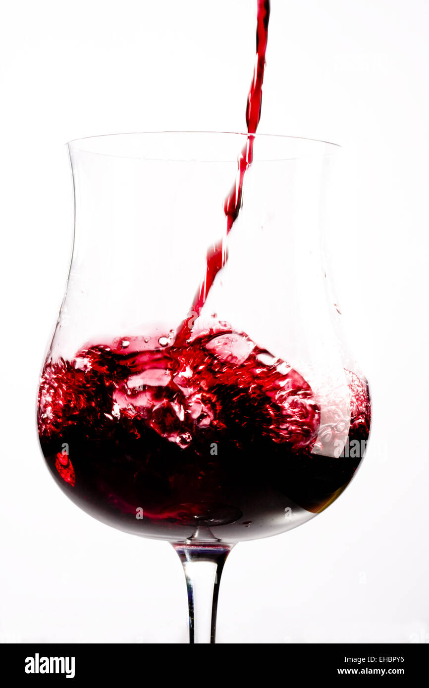 Vino rosso spruzzi in un bicchiere Foto Stock