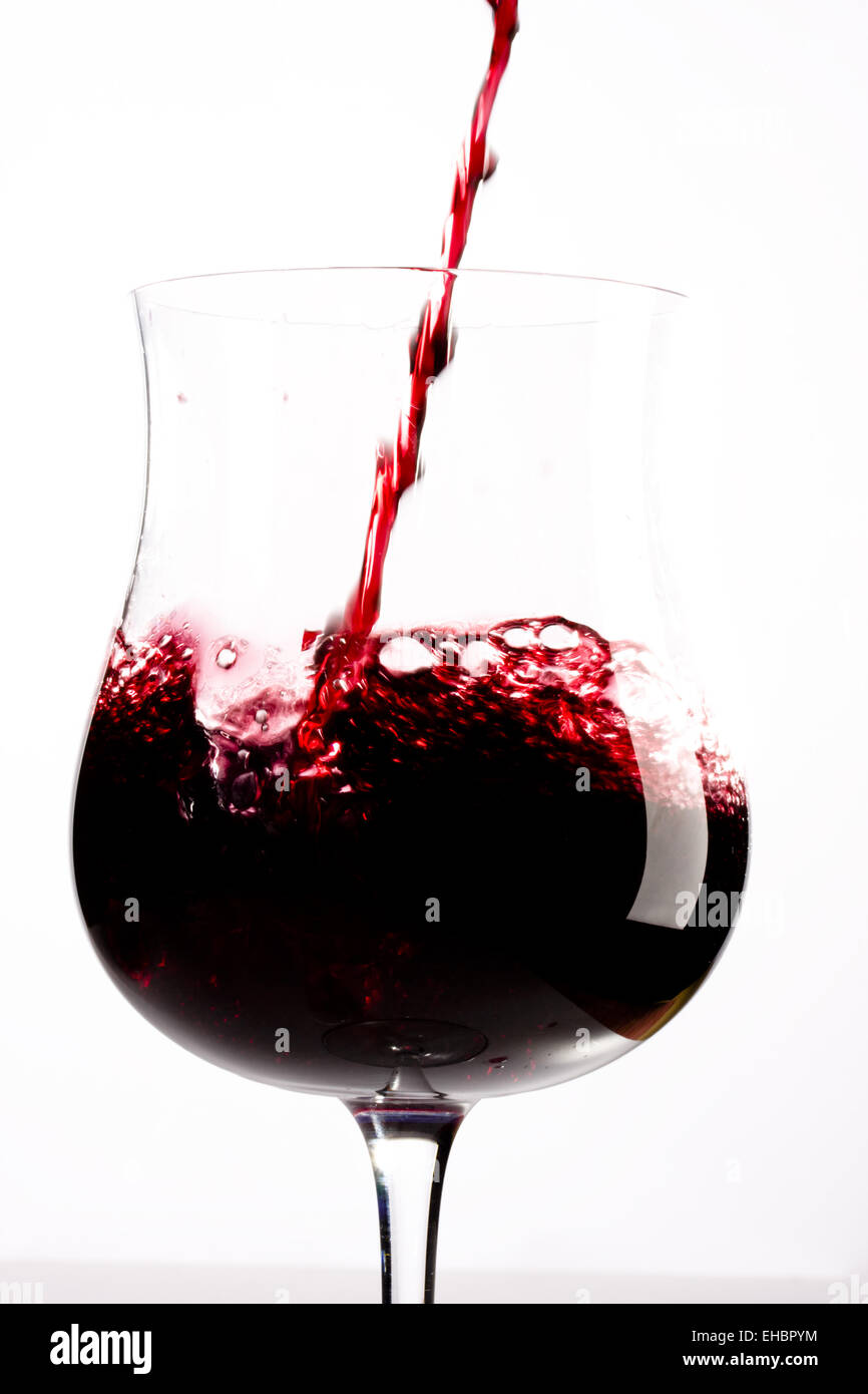 Vino rosso spruzzi in un bicchiere Foto Stock
