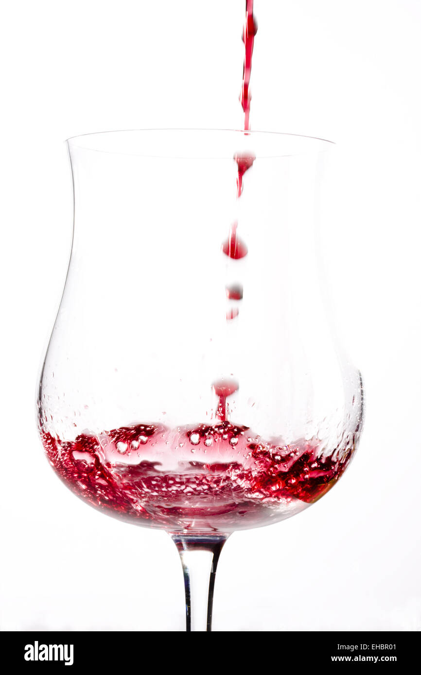 Vino rosso spruzzi in un bicchiere Foto Stock