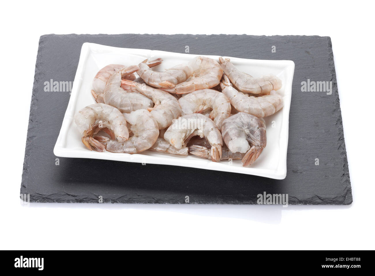 Raw gamberi crudi la piastra al di sopra della scheda di pietra. Isolato su sfondo bianco Foto Stock